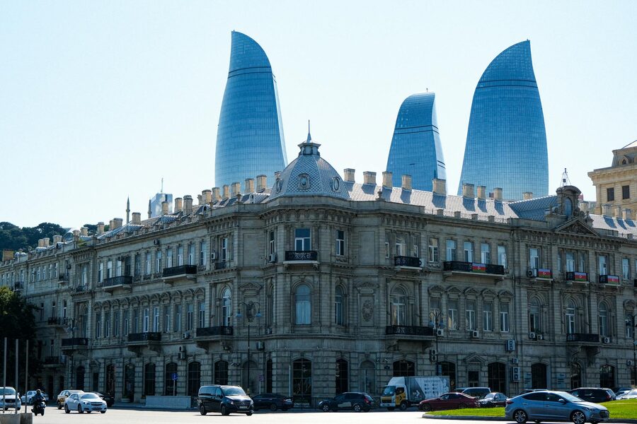 Baku Flame Towers rising behind an ornate historic building at sunset